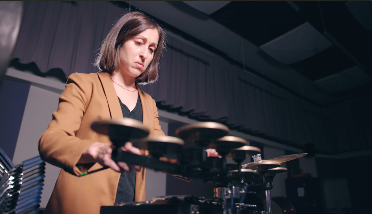 Abby Fisher wearing a tan blazer playing small symbols