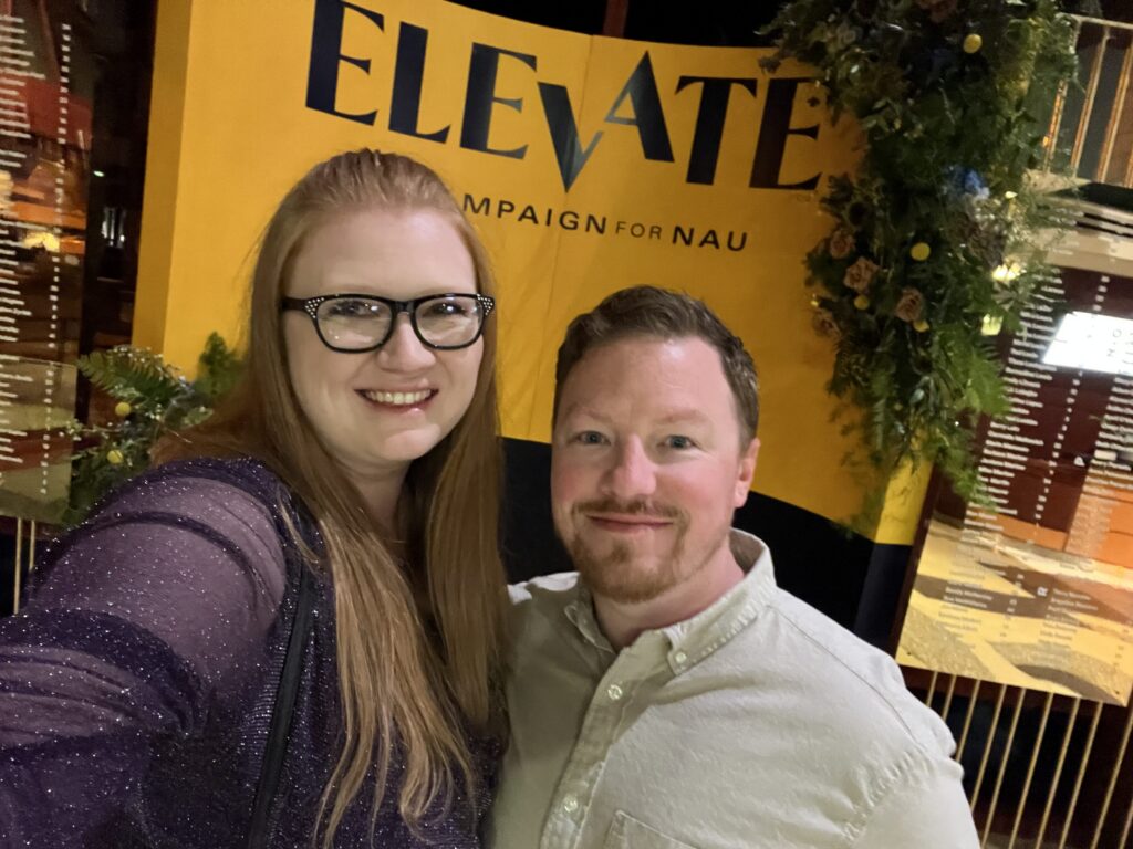Jocelyn Whiteneck dressed in dark purple sparkly shawl and male friend stand on the Elevate, the campaign for NAU platform, smiling at the camera