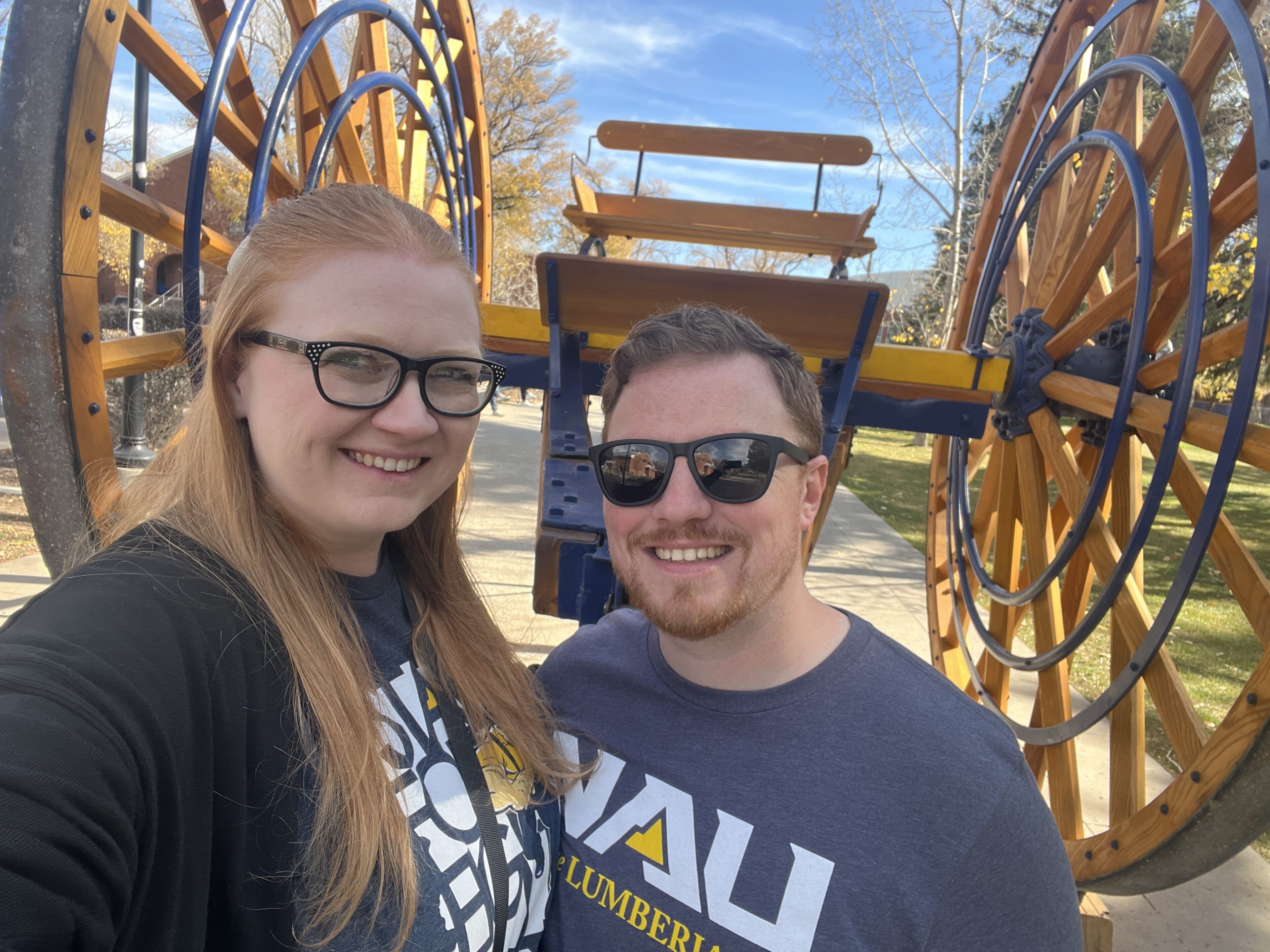 Jocelyn Whiteneck and male friend pose in front of the Homecoming logging wheel